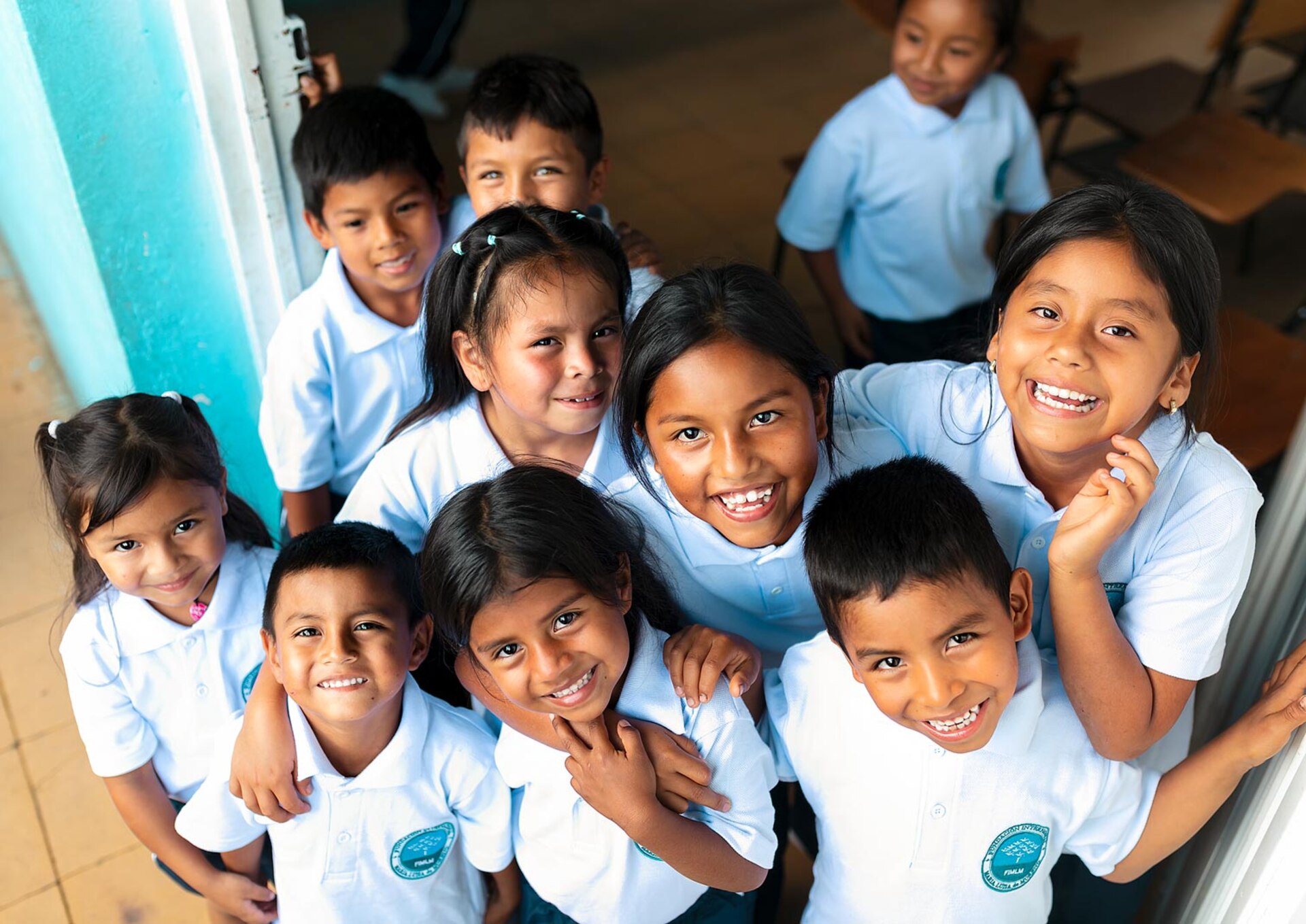 Grupo de niños y niñas beneficiarios de la Fundación, sonriendo con sus uniformes escolares.