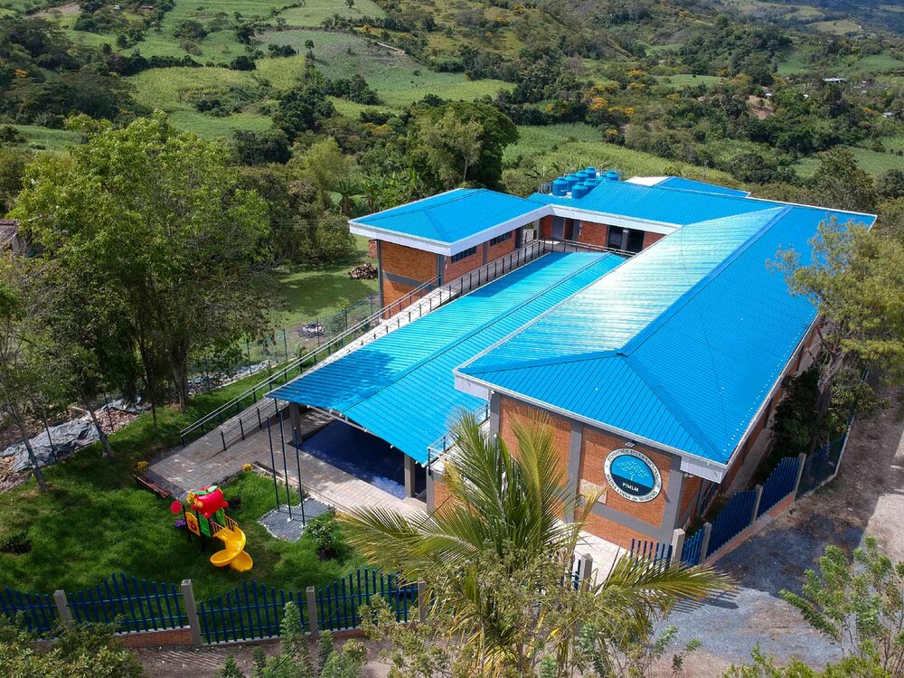 Vista aérea de la escuela de La Gabriela, Huila, con techo azul y zona de juegos infantiles.