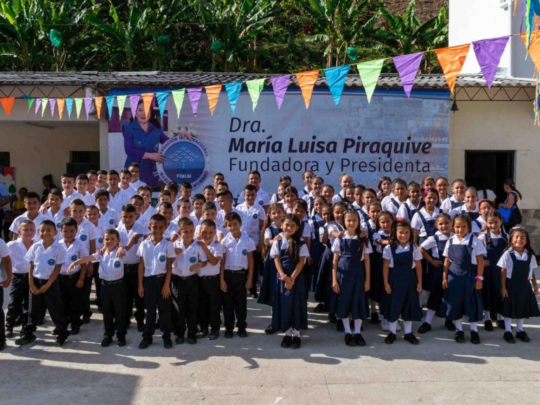 Los estudiantes del Centro Educativo Puente Umbría, con uniforme azul y blanco, posan frente a la sede adornada con banderines el día de la entrega.