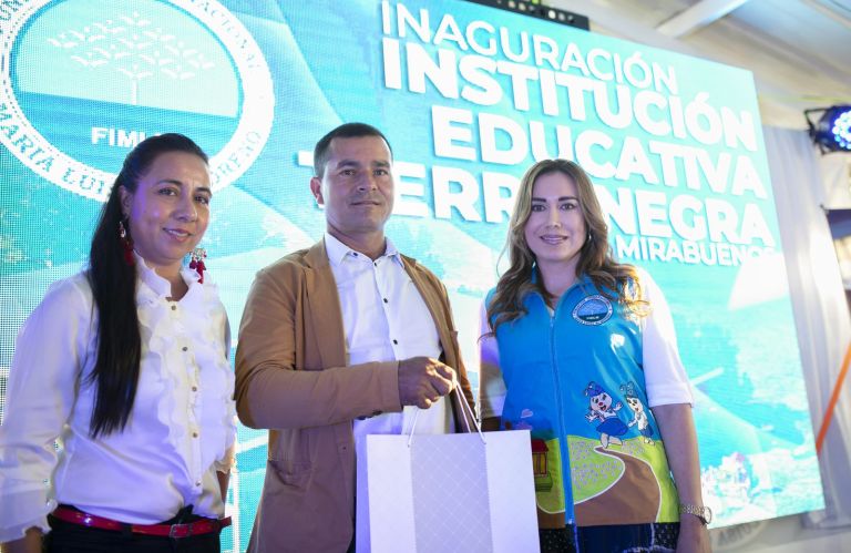 Representantes de la comunidad y de la Fundación posan frente a la pantalla de la ceremonia, que anuncia la inauguración de la Institución Educativa Tierra Negra, sede Mirabuenos.