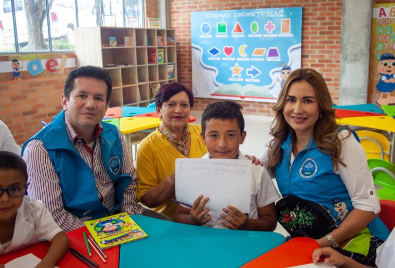 Un estudiante sostiene un cartel escrito a mano: «Gracias Doctora María Luisa y Doctora Ángela», rodeado por el equipo de la Fundación y una docente.