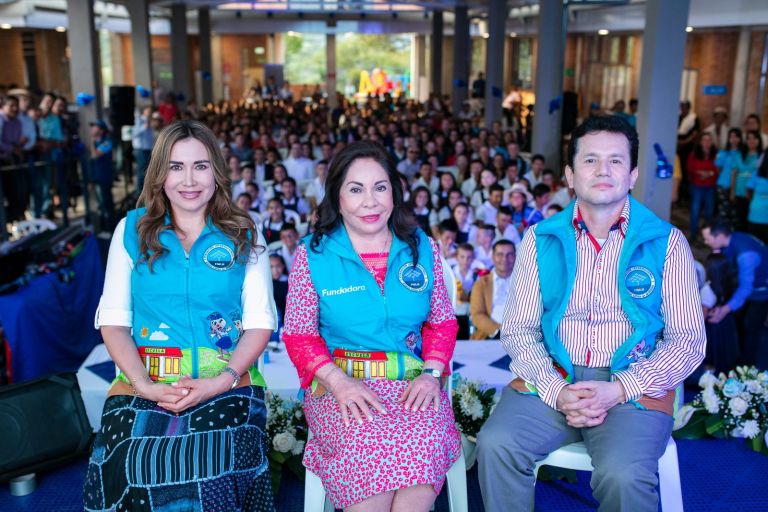 La Dra. María Luisa de Moreno y dos directivos de la Fundación sentados al frente del auditorio, con cientos de estudiantes y familias detrás.