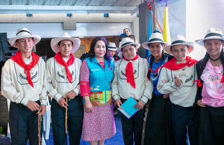 La Dra. María Luisa de Moreno posa con los estudiantes del grupo de danza, vestidos con trajes típicos y sombreros.