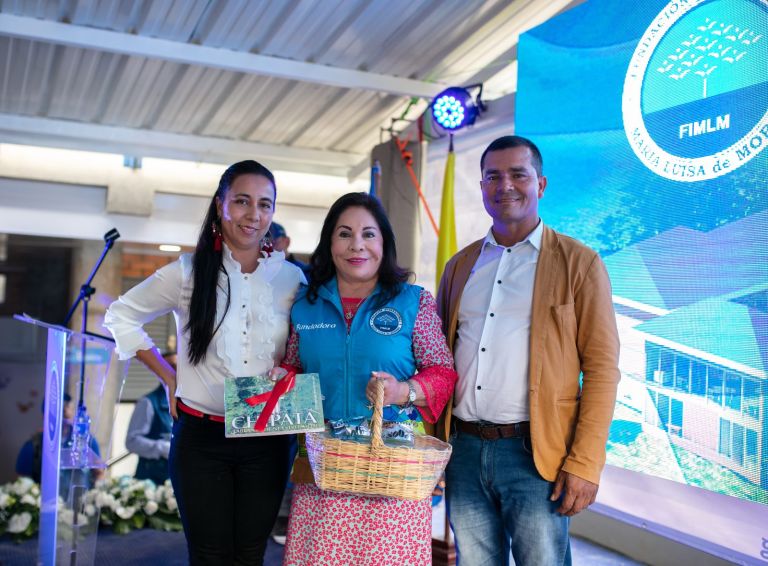 La Dra. María Luisa de Moreno recibe el libro «Chipatá, labranza de nuestro padre» y una canasta de café de manos del alcalde y de una representante del municipio.