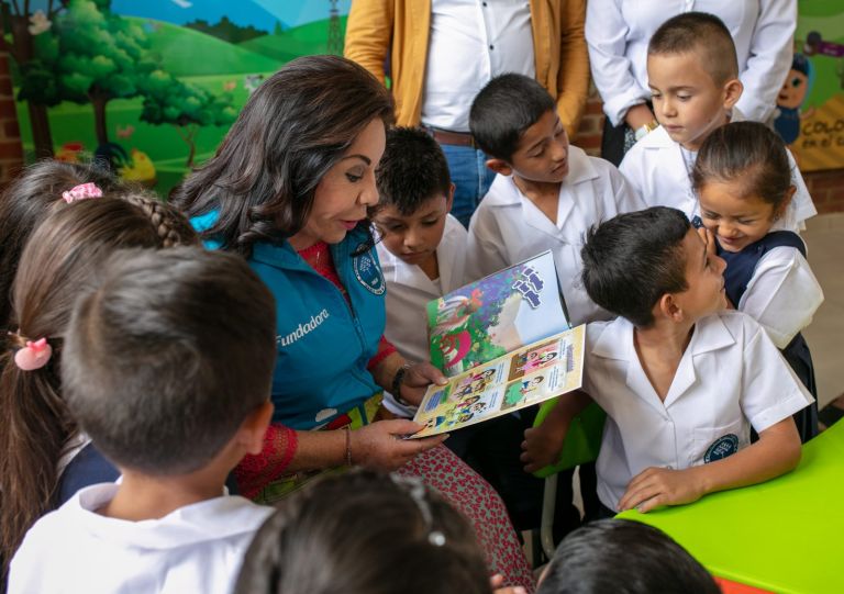La Dra. María Luisa de Moreno muestra a los niños las páginas de una historieta mientras ellos se asoman sonrientes.