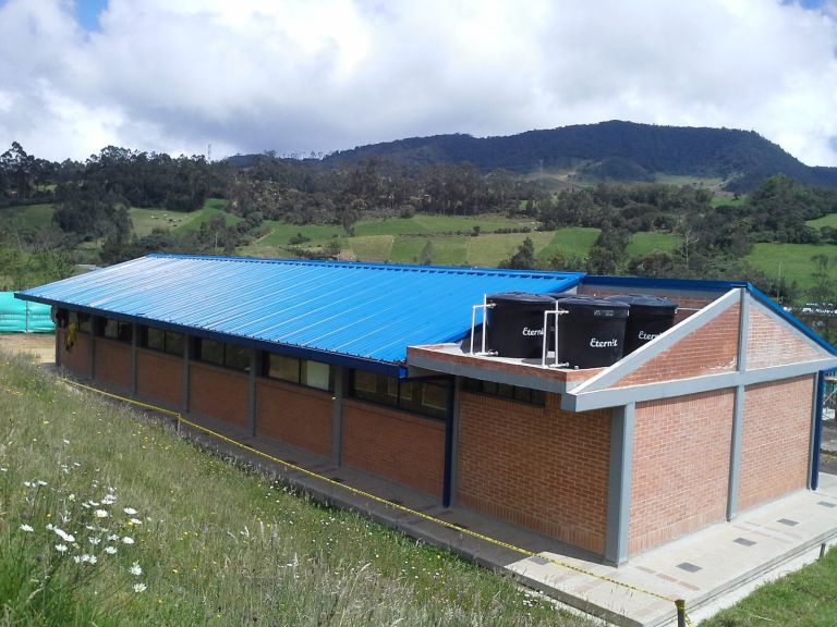 Uno de los bloques recién techado, con la cubierta azul montada y los tanques de agua instalados sobre la cubierta de ladrillo.
