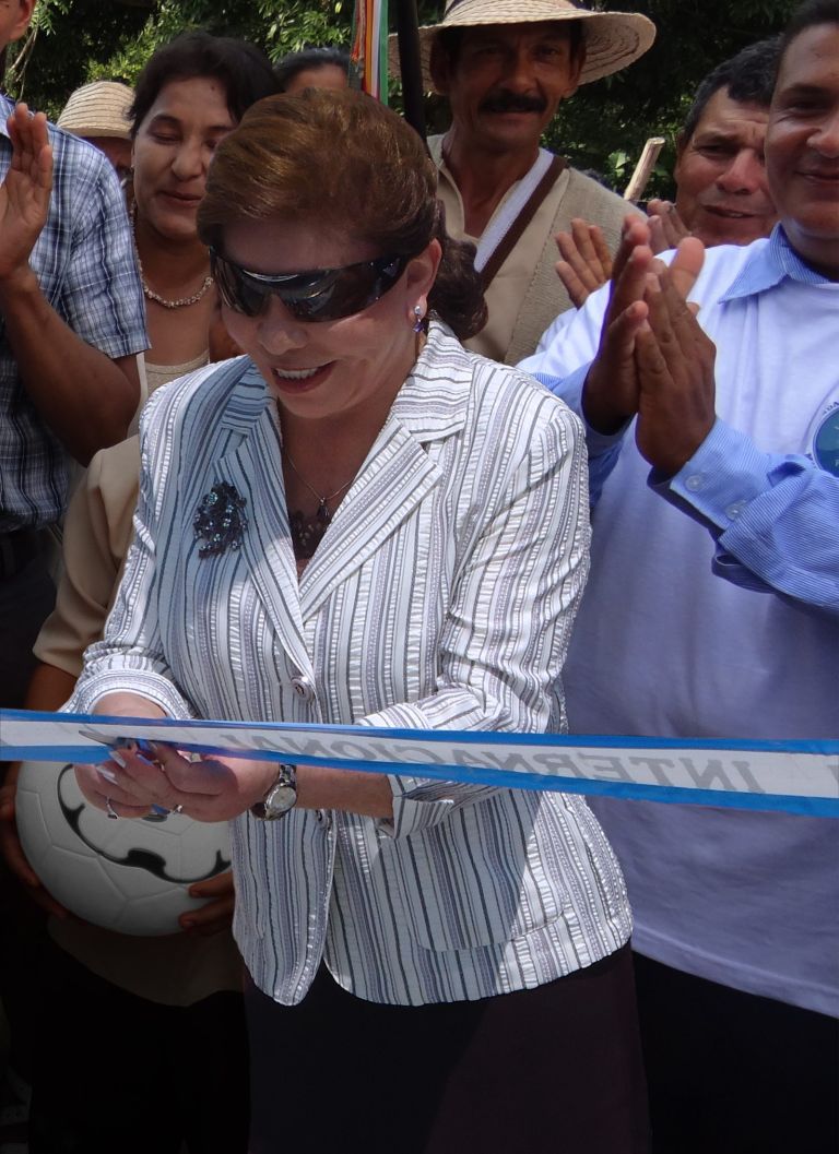 La Dra. María Luisa de Moreno cortando la cinta de inauguración, rodeada por la comunidad que aplaude.