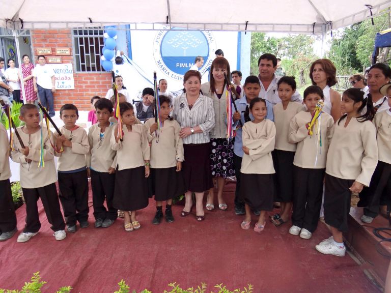 La Dra. María Luisa de Moreno con los estudiantes de la comunidad, vestidos con el traje tradicional y portando bastones con cintas de colores.