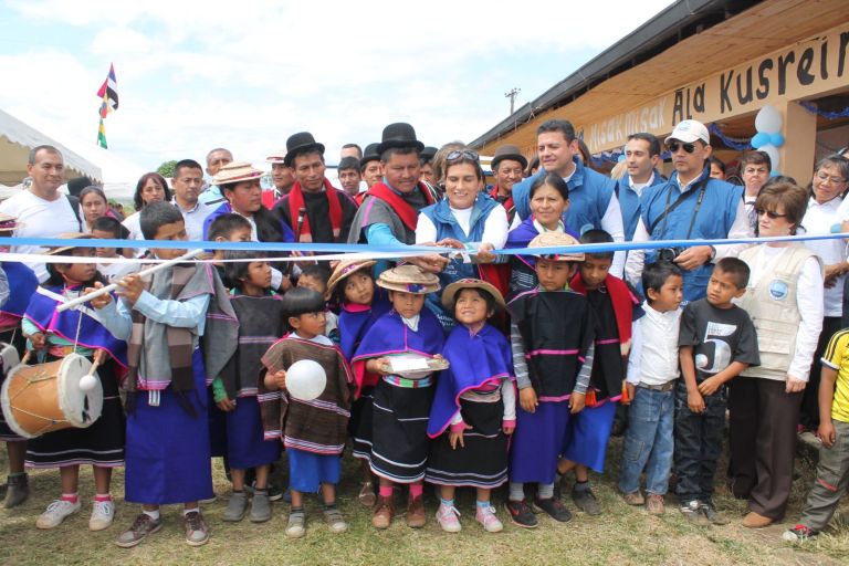 Corte de la cinta de inauguración frente a la escuela, cuyo letrero dice Misak Misak Ala Kusreinuk, entre autoridades misak, el equipo de la Fundación y los niños vestidos con el traje tradicional.