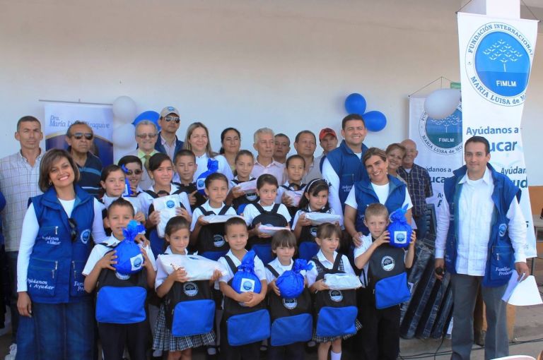 Niñas y niños con sus morrales y paquetes nuevos de la Fundación, junto a representantes de la Fundación, docentes y padres de familia.