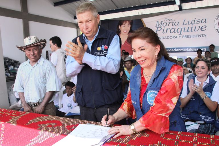 La Dra. María Luisa de Moreno firma el acta de entrega del centro etnoeducativo, mientras los asistentes aplauden.
