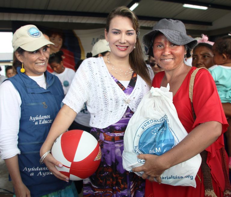 Una madre wayuu recibe un balón y un paquete de la Fundación, acompañada por dos representantes de la Fundación.