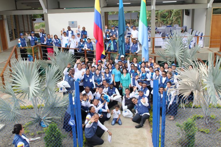 El equipo de voluntarios de la Fundación, con chalecos azules, saluda desde la entrada de la escuela el día de la entrega.