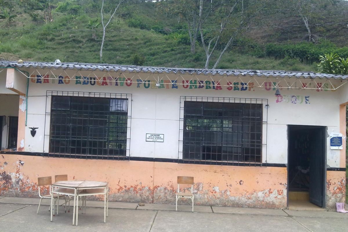 La escuela antes: la fachada con la pintura naranja descascarada y manchas de humedad, ventanas con rejas y el nombre del centro educativo pintado en letras de colores.
