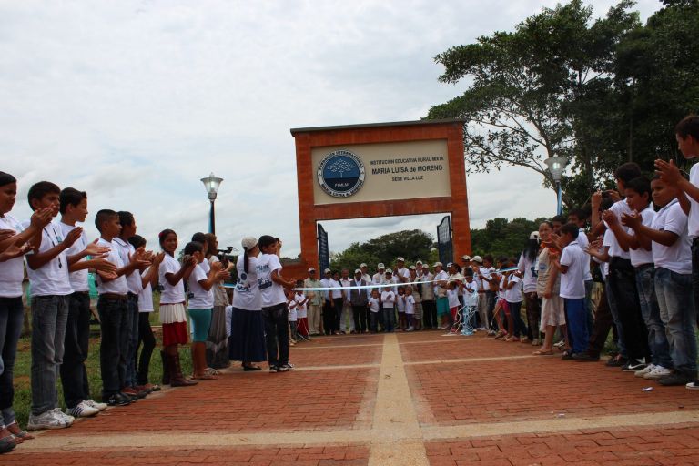Los estudiantes, con camisetas blancas, forman un pasillo de aplausos ante el portal de la nueva sede, con su nombre y el escudo de la Fundación, el día de la inauguración.