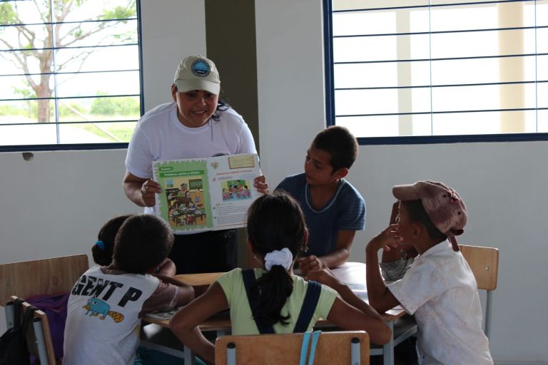 Una voluntaria de la Fundación muestra a los niños las páginas de un libro de texto en el aula nueva.