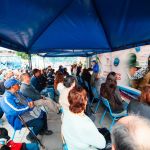 Personal militar y civil brindando atención médica bajo una carpa en un evento comunitario.