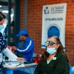 Personas recibiendo atención médica en una jornada de salud, con un cartel de oftalmología al fondo con el logo de la Fundación.