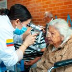 Una profesional realizando un examen visual a una mujer mayor.