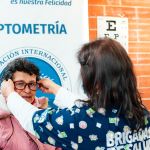 Una mujer realizando un chequeo ocular a una mujer mayor de edad en un evento comunitario.