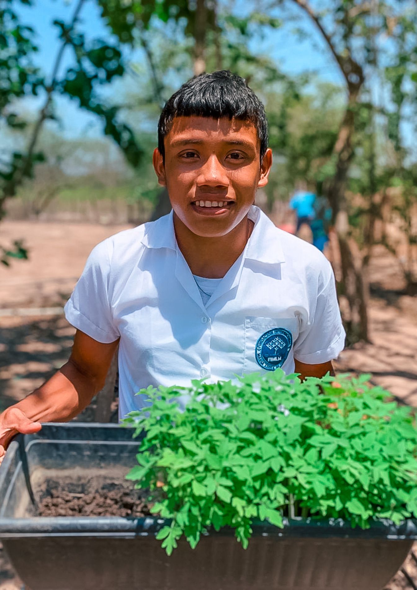 Niño Wayú sonriente, sosteniendo una matera