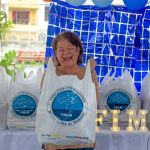 Rostro sonriente en beneficiaria del evento al recibir su kit de mercado.