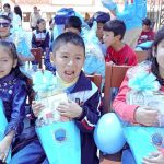 Dos niñas y un niño entre 5 y 7 años están mostrando muy felices el cono sorpresa que les entrego la Fundación.