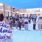 Los niños se encuentran de pie participando en los juegos y dinámicas que propones las animadores, y vemos un cartel de gracias a la Dra. María Luisa Piraquive