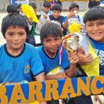 Tres niños están posando con el marco decorativo de fundación que ellos mismos elaboraron, algunos muestran sus regalos