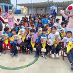 Un grupo de niños de 6 años sentados muestran con alegría el cono sorpresa que les regalo la Fundación