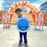 Un niño de pie, muy alegre tiene en sus manos un logo redondo de la Fundación.