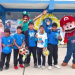 5 niños de 9 años de edad, posan para la foto mostrando los balones de regalo y los acompañan los personajes de Mario Bros