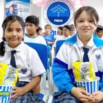 Dos niñas muy felices muestran el regalo que les entrega la fundación, un juego didáctico, un refresco y palomitas de maíz