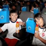 Una niña y un niño están felices mostrando su regalo y un delicioso refresco