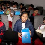 Dos niñas y un niño, ya están disfrutando del Telecine ellas muestran su regalo y el niño come su palomitas de maíz