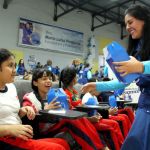 Dos niñas reciben con alegría los regalos de la Fundación que les entrega una voluntaria