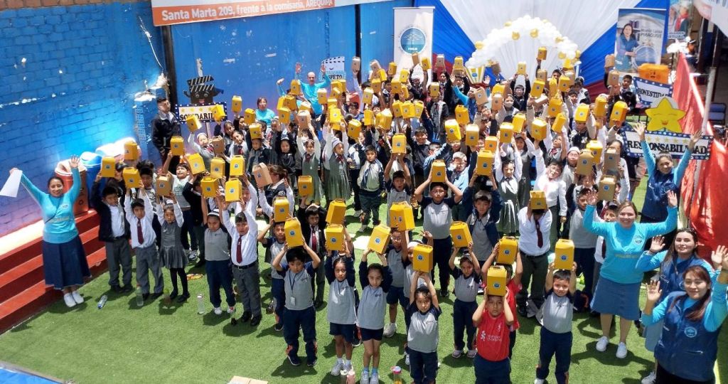 Todos los niños levantando su cajita sorpresa que contiene regalos, palomitas de maíz y bebidas