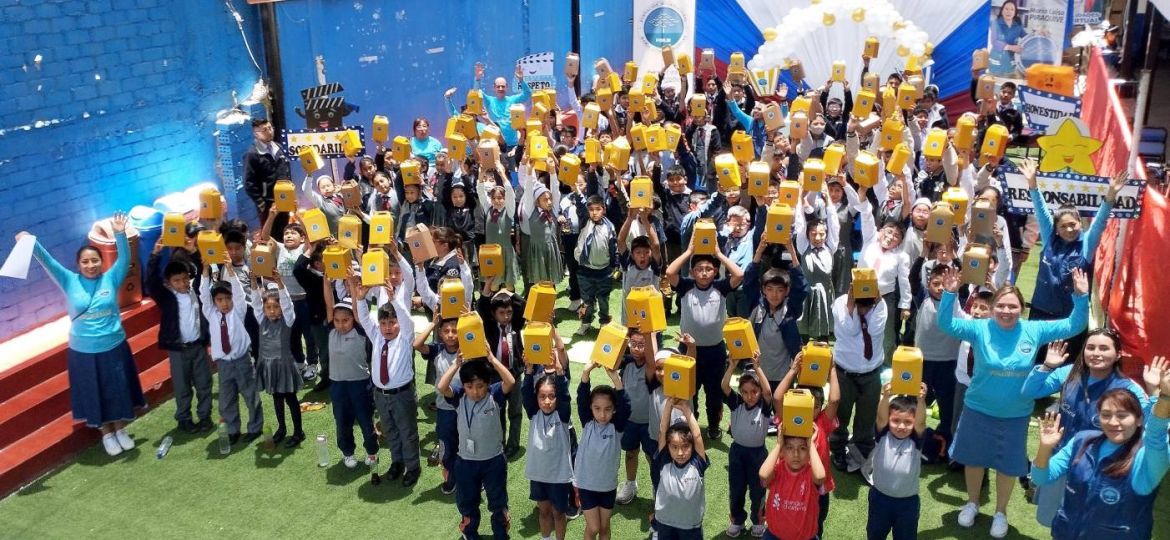 Todos los niños levantando su cajita sorpresa que contiene regalos, palomitas de maíz y bebidas