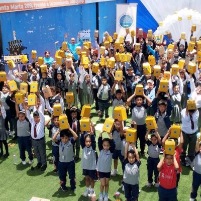 Todos los niños levantando su cajita sorpresa que contiene regalos, palomitas de maíz y bebidas