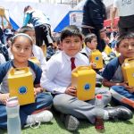 Una niña y dos niños muestran con alegría el regalo que recibieron