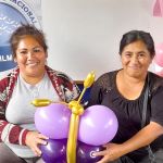 Dos mujeres muestran con alegría la mariposa de globos que aprendieron a realizar