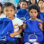 Dos niñas muy felices con sus mochilas con kits escolares