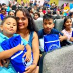 Una madre y sus hijos felices reciben los útiles escolares