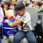 Niño feliz abre su mochila abre su mochila y regocija con lo que encuentra