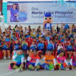 Niños, voluntarios y personajes animados posan juntos durante el cierre de un evento educativo con enfoque en valores y reciclaje.