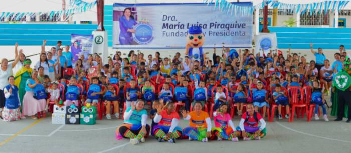 Niños, voluntarios y personajes animados posan juntos durante el cierre de un evento educativo con enfoque en valores y reciclaje.