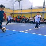 Niños corren tras la pelota en medio del partido