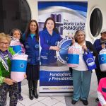 Seis beneficiadas sonríen alegremente mostrando su regalo, junto a ellas el show de Hormy