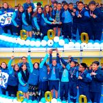 El equipo de futbol en compañía de los voluntarios levantan el trofeo