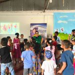 Beneficiarios llenos de alegría rodean a eco-héroe en una actividad interactiva